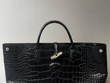 un sac à main en cuir de crocodile noir sur fond blanc