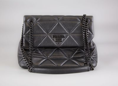 a black quilted purse with a chain strap on a white background