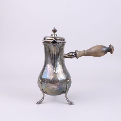an antique silver coffee pot with a wooden handle on a white background