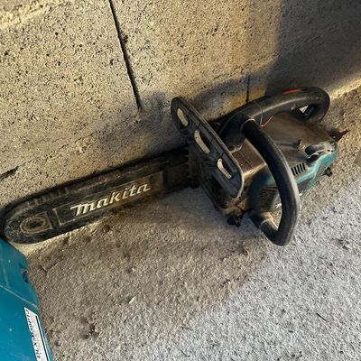 a chainsaw that is laying on the ground next to a wall