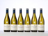 six bottles of white wine lined up on a table