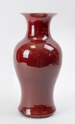a red vase sitting on a white surface