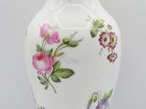 a white vase with pink and blue flowers on it