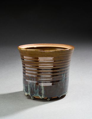 une tasse marron posée sur une table, sur fond noir