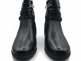 une paire de bottines en cuir noir ornées de boucles sur un fond blanc