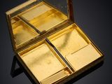 a small gold box with a pair of scissors inside of it
