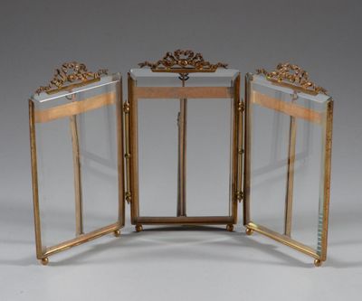 two gold - plated folding mirrors with ornate designs on the sides