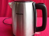 a silver and black electric tea kettle on a pink table