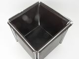 a black square container with metal legs on a white surface