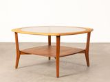 une table basse ronde avec un plateau en verre posée sur un sol en béton
