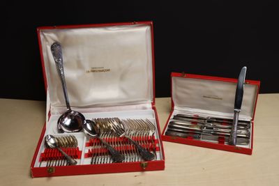 des couverts dans un étui rouge posé sur une table, à côté d'un couteau et d'une cuillère