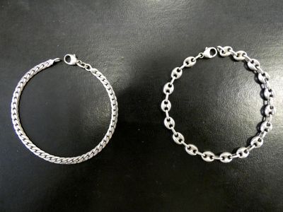 deux bracelets en argent posés sur une surface noire, sur fond noir
