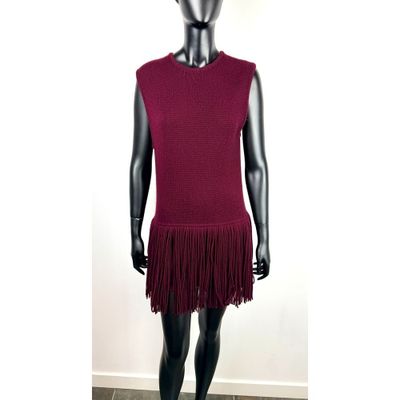 Le mannequin porte une robe rouge ornée de franges.