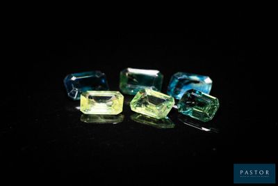 un gros plan sur trois pierres précieuses de couleurs différentes posées sur une surface noire