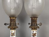 une paire de lampes en forme de vase, blanches et dorées, posées sur des socles, sur une surface grise