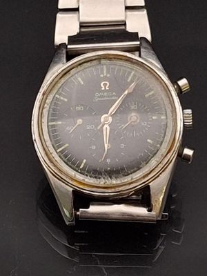 an image of a silver watch on a black surface with a black background
