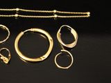 several gold rings, bracelets, and a chain on a black surface