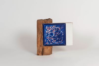 small blue and white square with red and white fish in it on a wooden stand