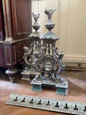 une horloge en argent posée sur un parquet, à côté d'une commode