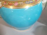 a blue tea pot with a gold trim and flowers on it