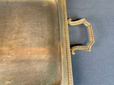 brass tray with handles and handles on a blue surface