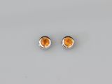 une paire de boucles d'oreilles en topaze orange posées sur une surface blanche