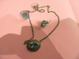 a necklace and earring set on a pink surface