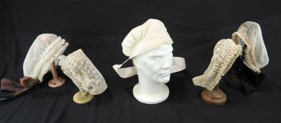trois chapeaux et un porte-chapeaux sur fond noir