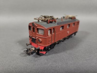 un petit train rouge sur les rails, sur un fond gris