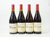 four bottles of wine are lined up on a white surface
