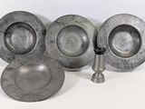 trois assiettes en argent et un bougeoir en argent posés sur une surface blanche