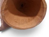 a hand holding a brown vase with writing on it