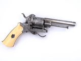 un petit revolver avec une crosse en bois posé sur une surface blanche