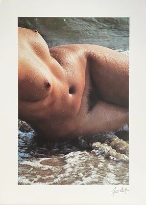 a picture of a man laying on the beach in the water