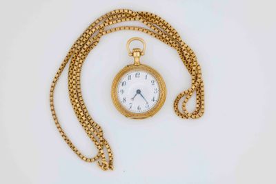 a gold pocket watch with a chain on a white surface