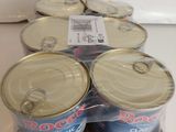six canettes de soda posées dans une boîte en carton sur un comptoir