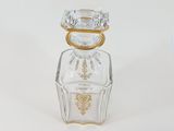 a clear glass bottle with a gold and white design on it