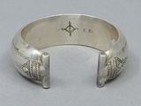 a close up of a silver bracelet with a compass on it