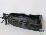 a black plastic boat shaped object on a white surface