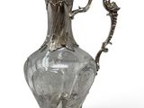 an antique silver plated glass pitcher on a stand on a white background