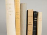 several books are stacked on top of each other on a gray surface