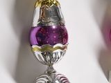 three silver and purple glass ornaments on a white surface