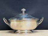 an antique silverplated bowl with a glass lid on a wooden table