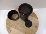 a camera lens sitting on a wooden plate next to a cup