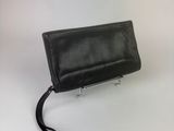 the black leather purse is sitting on a white surface