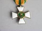 a gold cross with a green and yellow ribbon around it