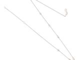 un gros plan d'un collier et d'une paire de ciseaux posés sur une surface blanche