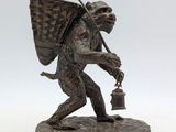 bronze statue of a monkey with a basket on his back holding a lantern