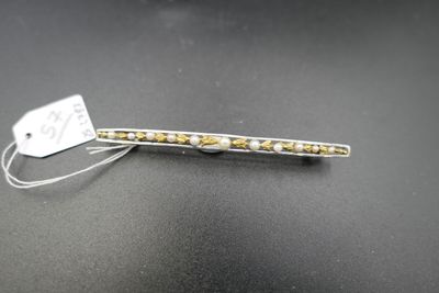 une barrette à cheveux argentée et dorée à laquelle est attachée une étiquette