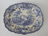 an old blue and white plate with a picture of a house in the background